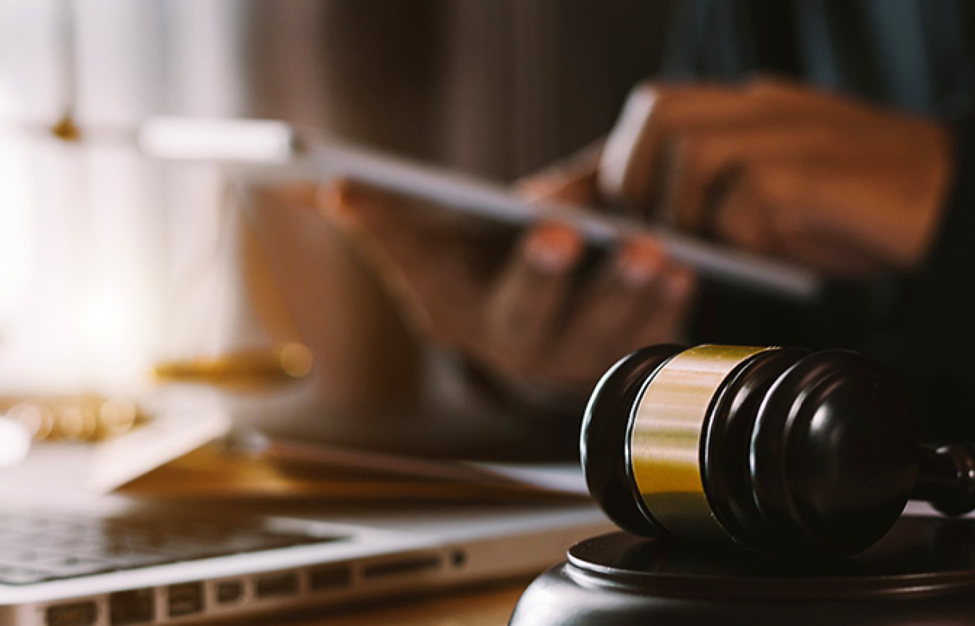 gavel with computer and person on tablet in background