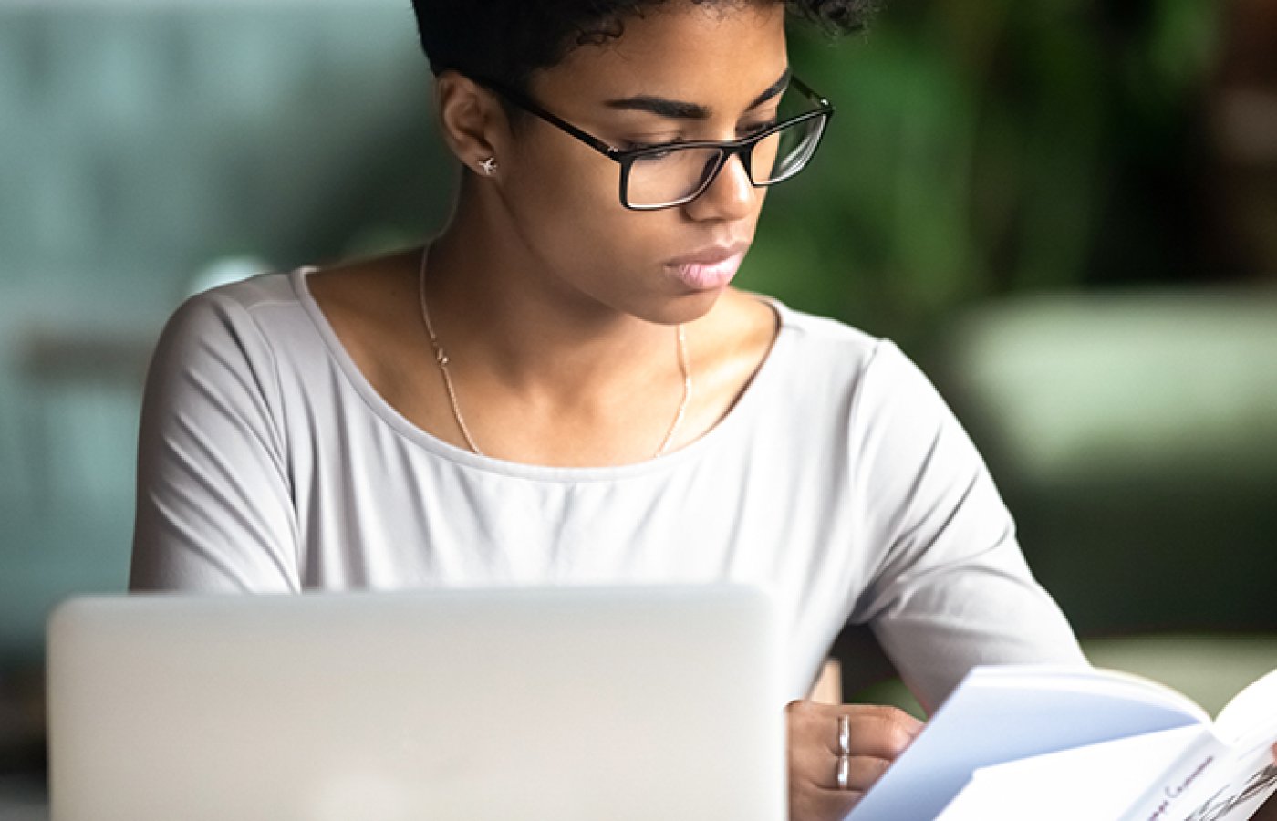 person on laptop looking at book