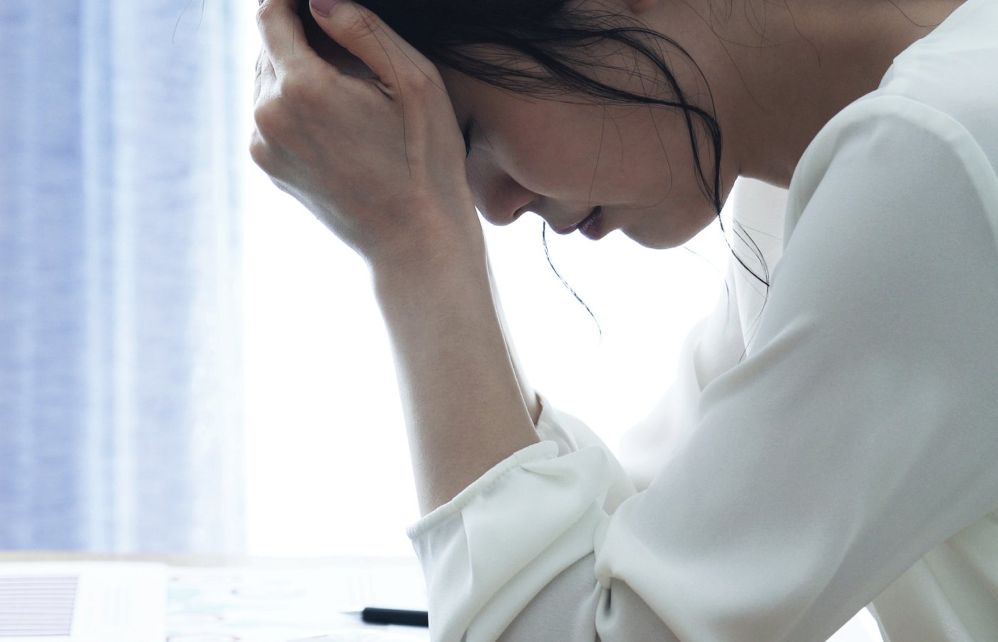 woman looking down with hand on her head