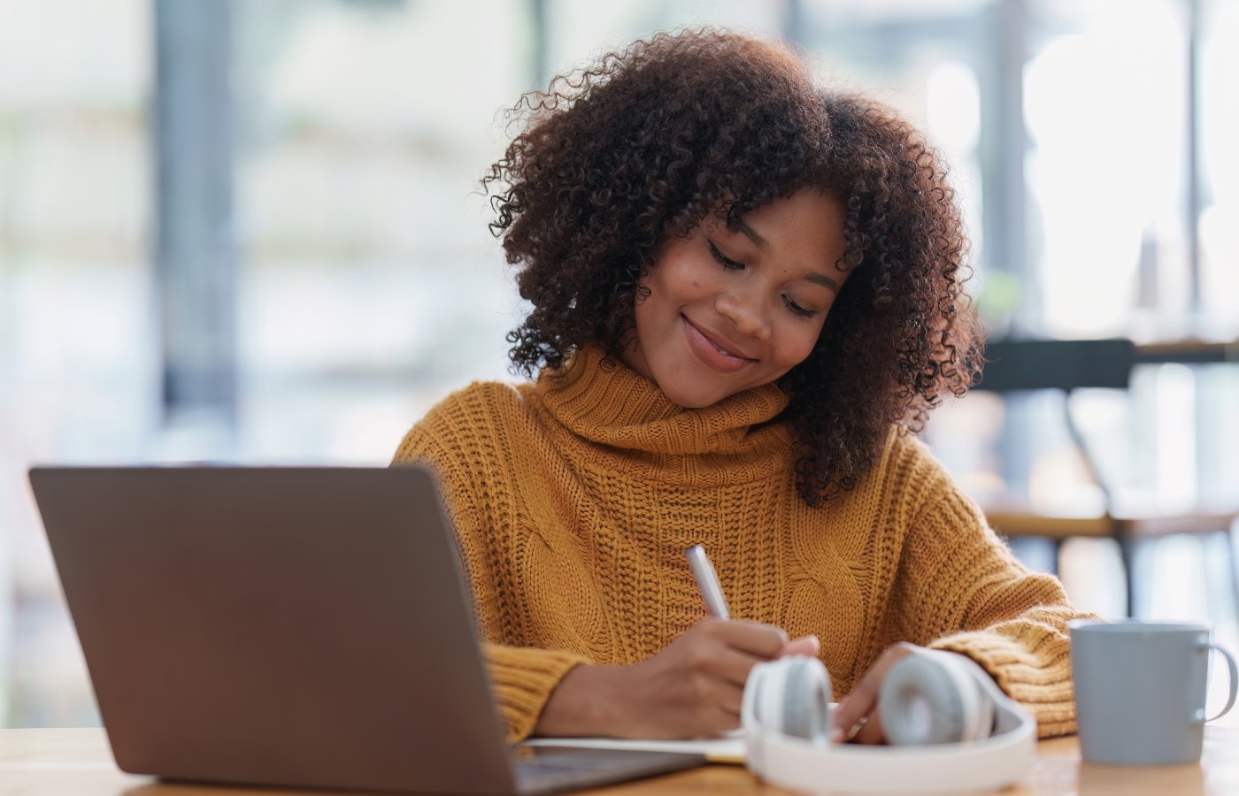 Young woman working at a laptop and writing notes