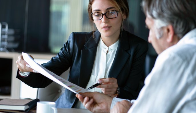 woman in an office environment pointing to papers and discussing with a man