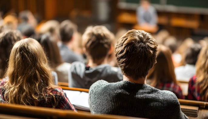 Rows of students in class a lecture hall. View is from the back of their heads