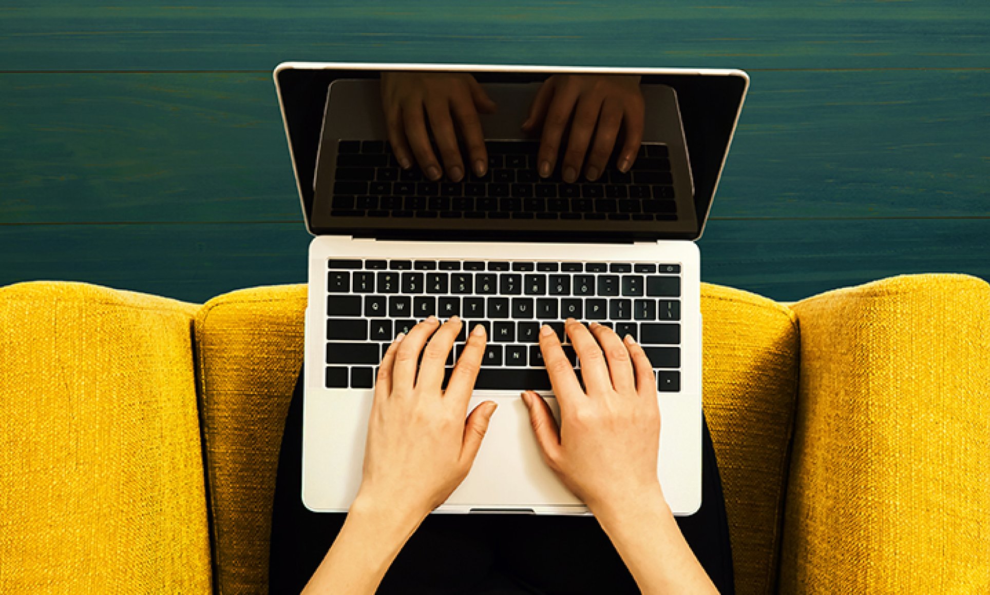 hands on computer keyboard on yellow chair