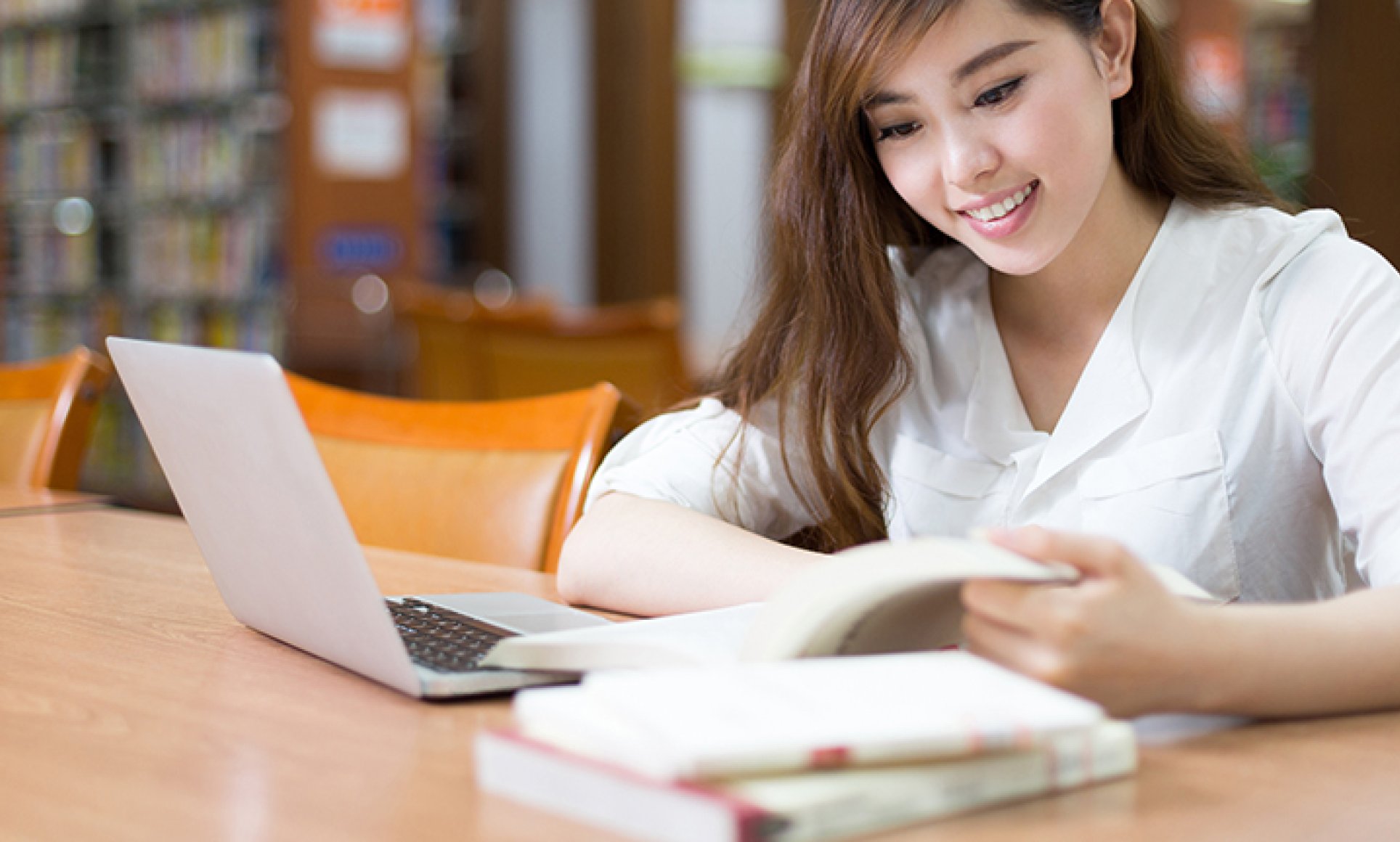 Woman in library looking at papers in front of computer 