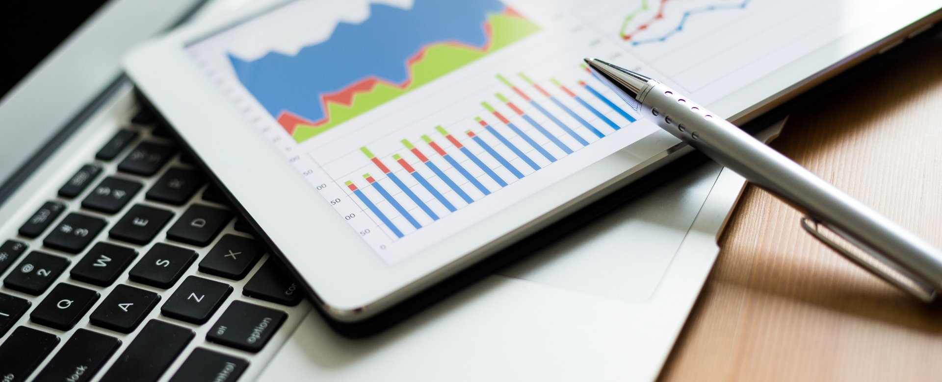 close up of computer and tablet with line and bar graphs