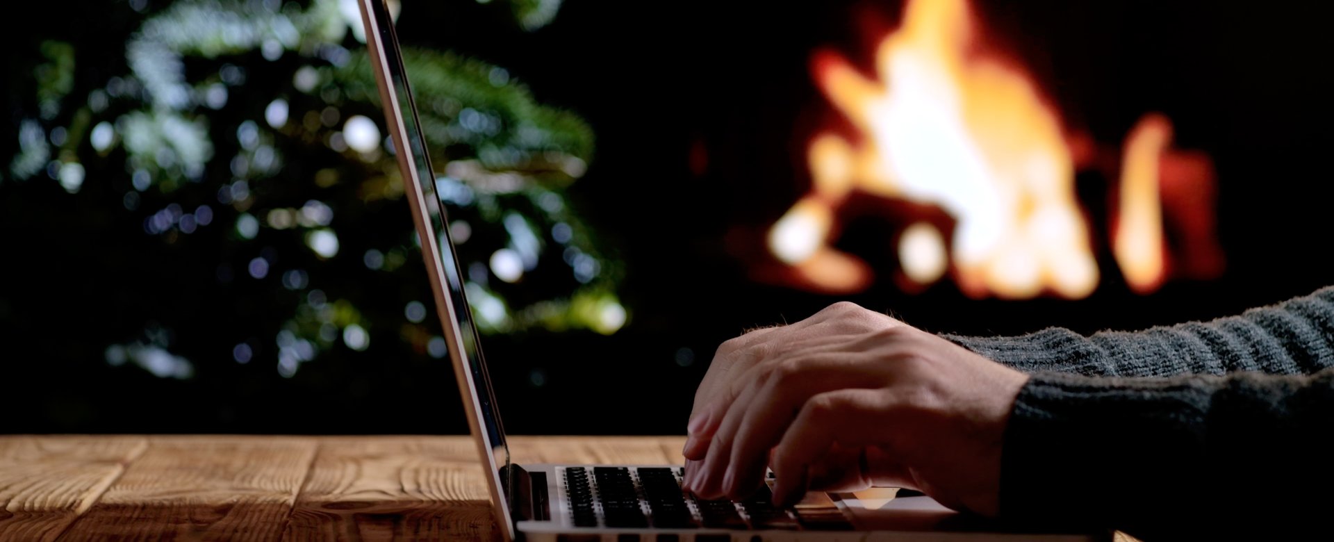 hands on laptop with fireplace in background