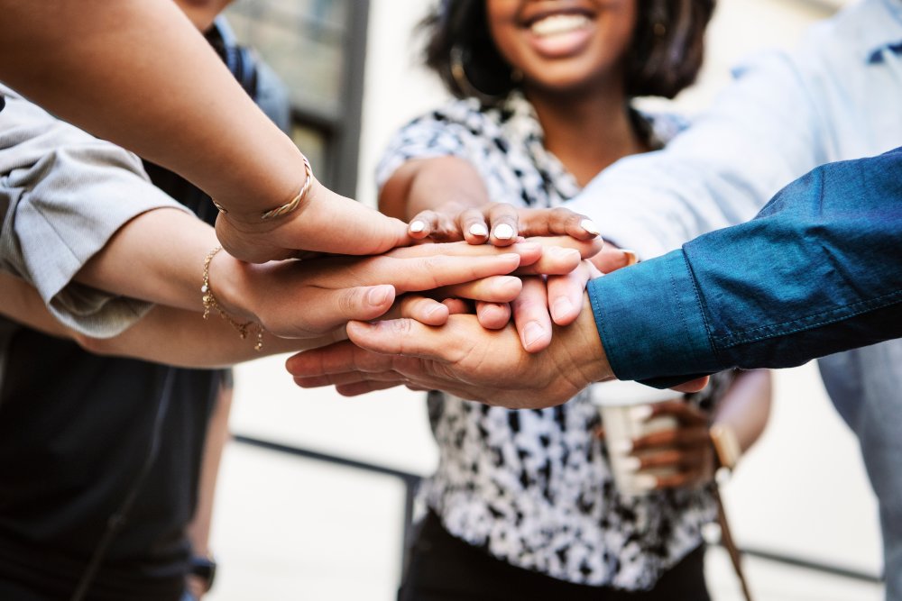 People of different races putting hands on top of each other