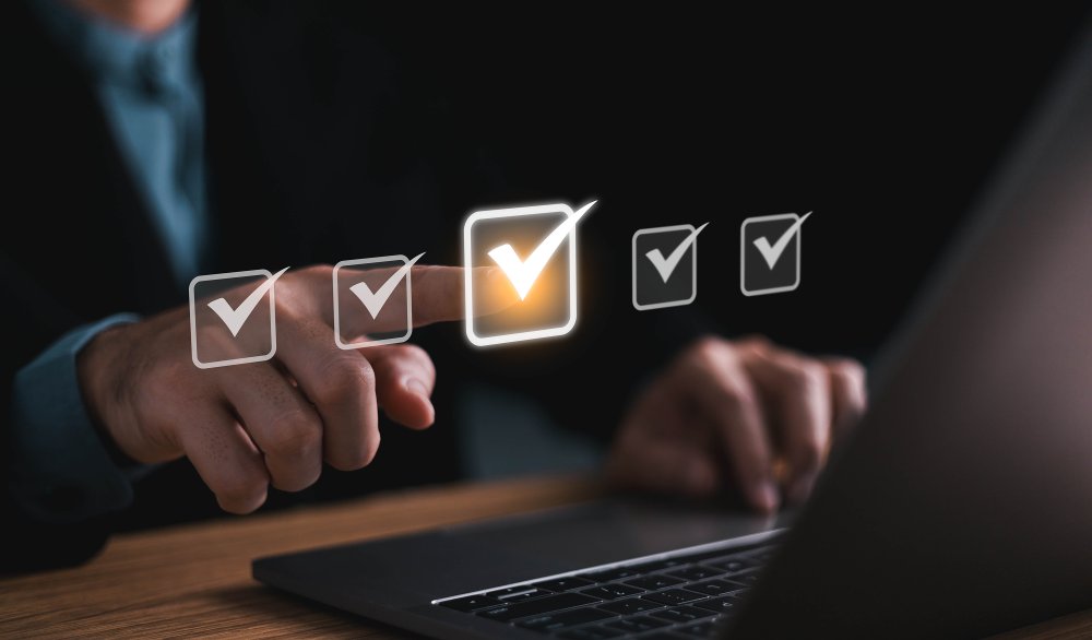 close up of a person at a computer and pointing to a row of abstract checkmarks in the air 