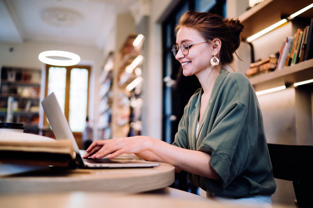 young woman working at a laptop in a library