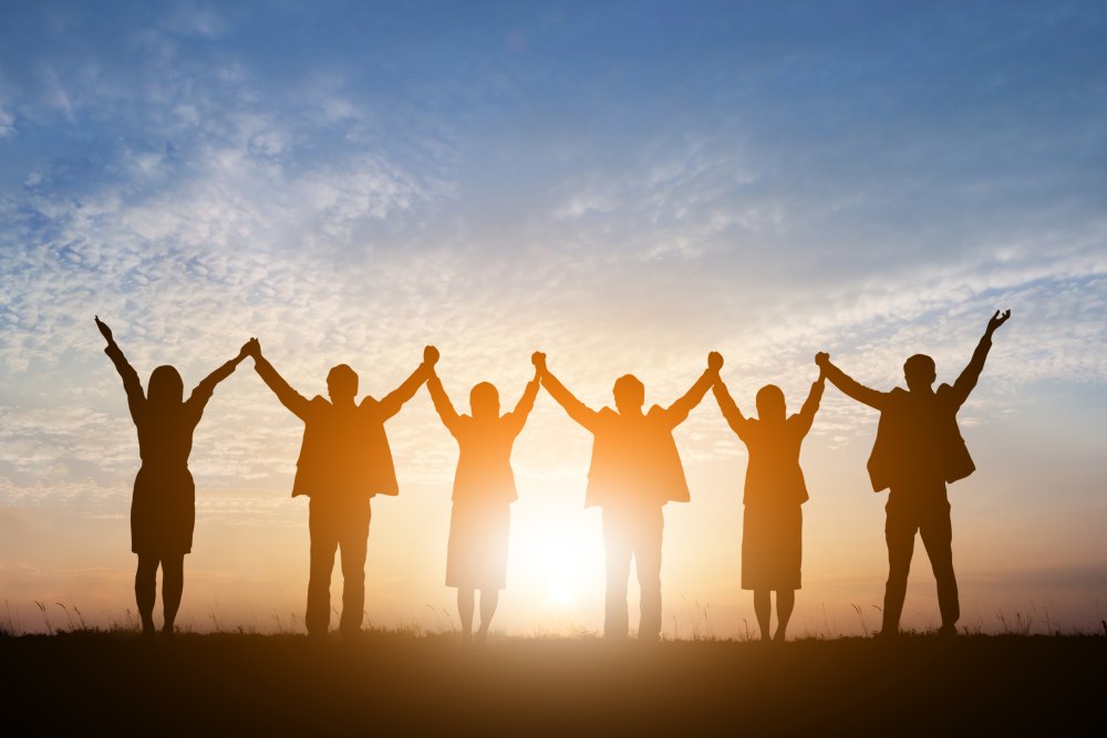 people in a row holding hands raised up to the sky