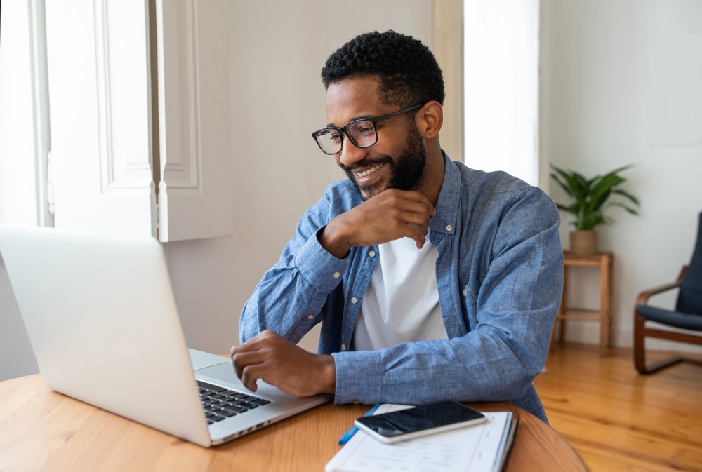 man working at a laptop and smiling